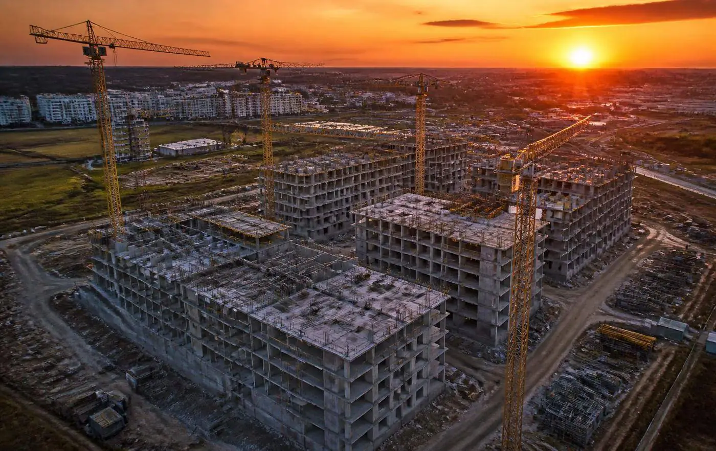 Grúas en una promoción residencial en construcción al atardecer